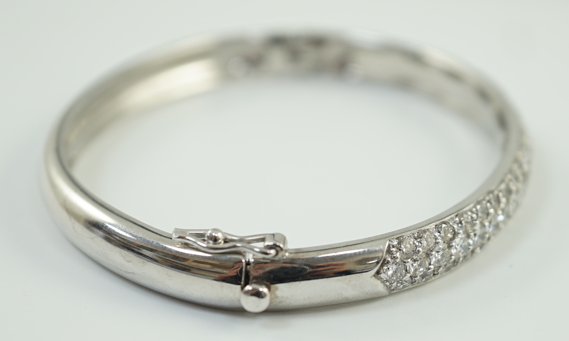 A modern 18ct white gold and pave set diamond hinged bangle